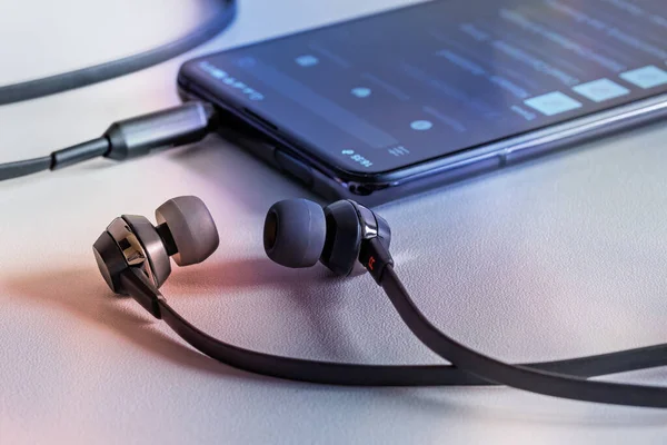 Akıllı telefon ve telli müzik kulaklığı. En sevdiğim müziği dinlerim. Stüdyo fotoğrafı, yakın çekim..
