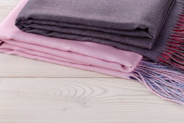  Kahverengi ve pembe eşarplar, açık renkli ekose kumaşlar, ahşap arka plan. Kaşmirden soğuk hava aksesuarları. Boşluğu kopyala.