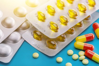 Mavi arka planda çeşitli tabletler, kapsüller ve vitaminler var. İlaç sanayisi. Eczane.