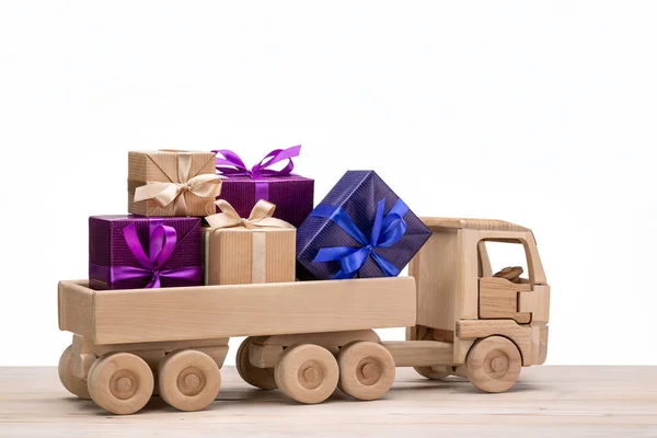 Truck with gifts in colorful boxes. Wooden toy car. White background, copy space, holiday concept.