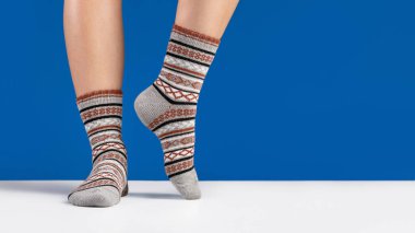 Kadın bacaklarında sıcak çorap, mavi arka plan. Stüdyo görüntüsü, kopyalama alanı.