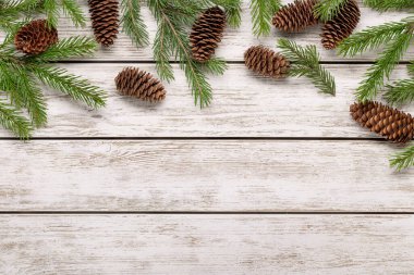 Kış tatili konsepti ve tebrikler. Hafif ahşap zemin üzerinde ladin dalları ve koniler, boşluğu kopyala.