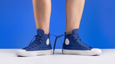 Kadınların bacaklarındaki bağcıklara bağlı bir çift mavi spor ayakkabı. Spor ve seyahat ayakkabıları..