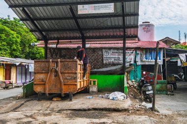 Balikpapan, Endonezya - 3 Ağustos 2025. Endonezya 'nın doğusundaki Balikpapan şehrinde büyük bir çöp konteynırında çalışan bir çöpçünün günlük yaşamını gösteren samimi bir fotoğraf..