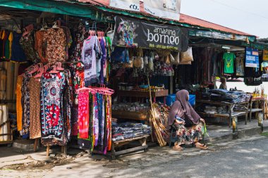 Balikpapan, Endonezya - 3 Ağustos 2025. Yerel pazarda renkli kıyafetler, kumaşlar ve hediyelik eşya satan bir dükkan..