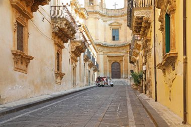 Noto, Sicilya, İtalya - 25 Ağustos 2019: Noto Antik sokak, Sicilya, Piaggio araba ve turistler ile