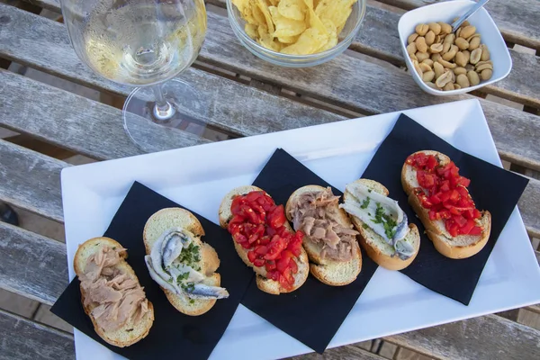 Sicilian appetizers. Bread with tomatoes, anchovies and tuna fish served with a glass of wine.