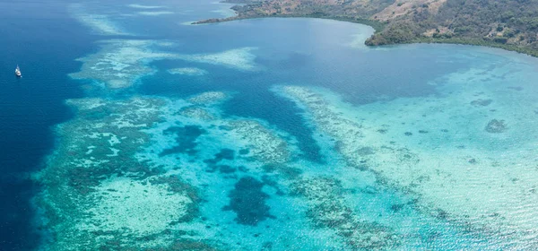 一艘小型 Pinisi 帆船停泊在印度尼西亚兰勿刹岛的美丽珊瑚礁附近 这个偏远的热带地区 在珊瑚三角内 拥有非凡的海洋生物多样性 — 图库照片