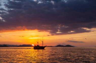 Pinisi schooner Komodo Ulusal Parkı, Endonezya'da günbatımında sakin deniz yola çıkacak. Bu tropikal bölge tüplü dalgıçlar ve snorkelers doğa severler için popüler bir yer.