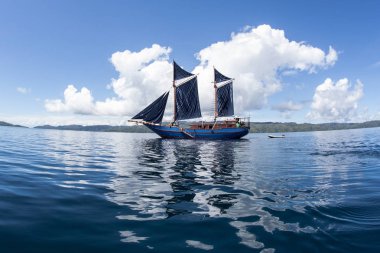 Güzel bir Pinisi schooner Raja Ampat, Endonezya sakin sularda yelken. Bu uzak, tropikal bölge inanılmaz deniz biyoçeşitliliği nedeniyle Mercan Üçgeni kalbinde olarak bilinir.
