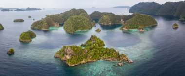 Seen from above, a shallow coral reef surrounds a remote island in Raja Ampat, Indonesia. This biodiverse region is known as the 