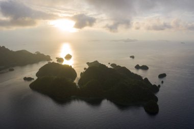 Raja Ampat, Endonezya, uzak kireçtaşı Adaları batan güneşin kontrast. Bu biodiverse bölge, onun muhteşem deniz yaşamı nedeniyle Mercan Üçgeni 