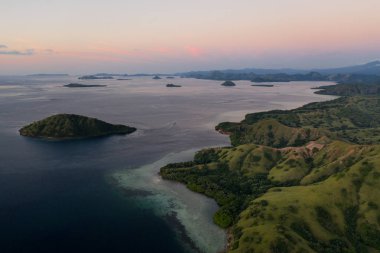Kuş bakışı bakıldığında, alacakaranlık Komodo Milli Parkı içinde bulunan engebeli adalar üzerine düşüyor, Endonezya. Bu tropik alan, deniz biyolojik çeşitliliği nin yanı sıra ejderhaları ile de bilinir..