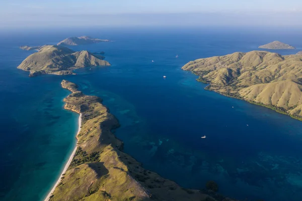 Seen from a bird\'s eye view, the blue Pacific Ocean surrounds the rugged island of Komodo in Indonesia. This tropical area is known for its marine biodiversity as well as its dragons.