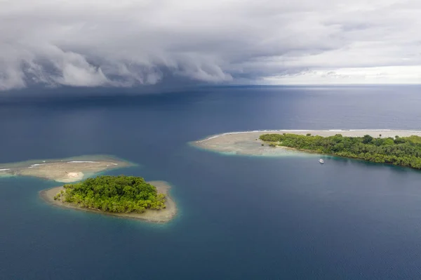 Rain clouds sweep over the Pacific Ocean approaching small, tropical islands in Papua New Guinea. Squalls are common in the tropics and they come and go quickly.