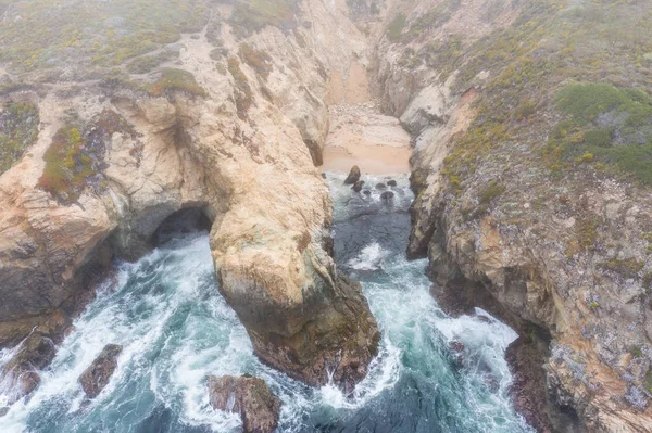 Seen from a bird\'s eye view, the Pacific Ocean washes against the rocky and rugged coast south of Monterey in Northern California. This beautiful area runs parallel to the famed Pacific Coast Highway.
