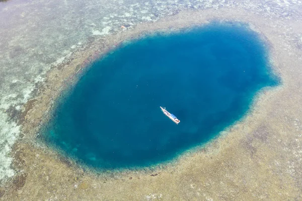 A blue hole is found amid a shallow reef flat on the island of Sebayor in Komodo National Park, Indonesia. Blue holes originally formed as limestone sink holes when sea levels were lower.
