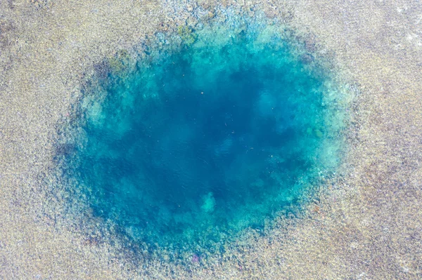 A blue hole is found amid a shallow reef flat on the island of Sebayor in Komodo National Park, Indonesia. Blue holes originally formed as limestone sink holes when sea levels were lower.