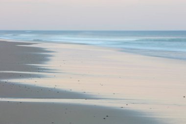 Cape Cod, Massachusetts 'teki bir plaja vururken Atlantik Okyanusu' nun renkleri sakin bir alacakaranlıkla kaplanır. Bu manzaralı New England yarımadası favori bir yaz tatili mekanıdır..