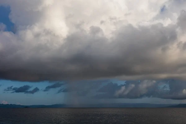 低い雲は インドネシアのラジャアンパットの穏やかな海で雨のシャワーを放出します 熱帯地方は素晴らしい海洋生物多様性で知られています — ストック写真