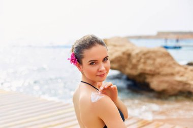 Güneş koruyucu krem uygulayarak kadının omuz bronzlaşmış. Cilt Bakımı. Güneş koruma güneş kremi vücut. Nemlendirici losyon geri Bikini kadın smear.