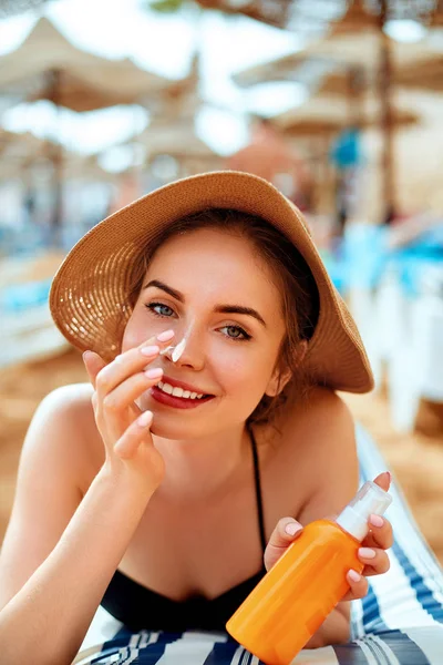 Sunscreen / sunblock. Woman putting solar cream on nose smiling  beautiful summer day. Skincare. Girl applying sun cream