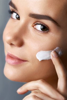 Çekici kız Anti-Aging Krem onun yüzüne koydu. Portre portre sağlıklı pürüzsüz bir cilt ile kızın