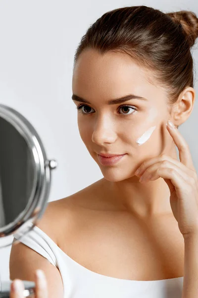 Wanita Muda Mencari Cermin Kosmetik Dan Menerapkan Krim Lotion Wajah — Stok Foto