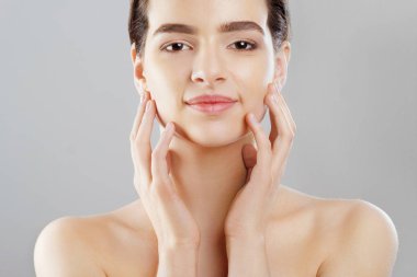 Güzellik ve Spa kavramı. Güzel genç kadın temiz taze cilt ile değmek kendi yüz ve Smiling.Facial tedavi. Kız erkek doğal Makeup.Cosmetology ile.