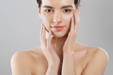 Güzellik ve Spa kavramı. Güzel genç kadın temiz taze cilt ile değmek kendi yüz ve Smiling.Facial tedavi. Kız erkek doğal Makeup.Cosmetology ile.