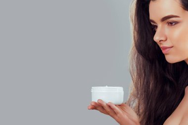 Cilt Bakımı. Güzellik kavramı. Kozmetik krem tutan genç güzel kadın. Yumuşak deri ve çıplak omuz, model makyajlı ışık çıplak, kadın tutarak onun elinde krem nemlendirici portresi. Cilt koruma ve Dermatoloji.