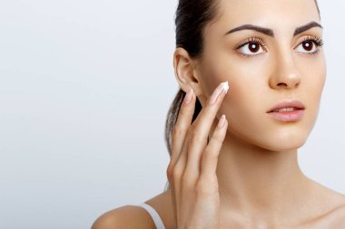 Yüz bakımı. Erkek Cream.Portrait olan genç kadın kozmetik krem cilt üzerinde uygulamak. Yüz dokunmadan yumuşak cilt, doğal makyaj güzellik ürünü ile güzel kız closeup. Yüksek çözünürlük
