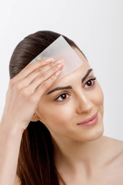 Cilt bakımı. Genç bir kadın, lekeleme kağıtları kullanarak yüzünden yağ çıkarıyor. Pürüzsüz ve sağlıklı ciltli güzel bir kadının fotoğrafı. Güzellik konsepti