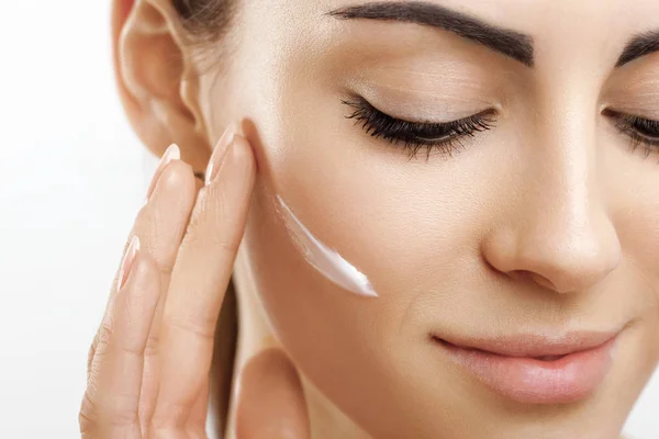 Yüz bakımı. Erkek Cream.Portrait olan genç kadın kozmetik krem cilt üzerinde uygulamak. Yüz dokunmadan yumuşak cilt, doğal makyaj güzellik ürünü ile güzel kız closeup. Yüksek çözünürlük