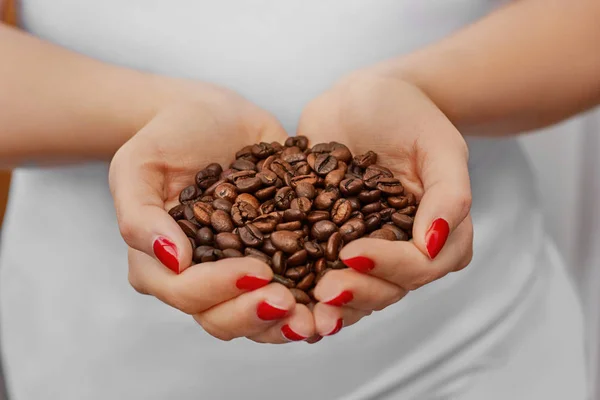 Handful of fresh organic coffee beans. Food and drink coffee background. Coffee beans in young girl hands