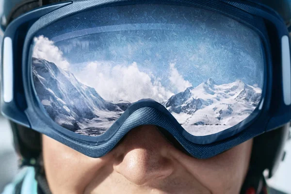 雪が降った山の反射で男のスキーゴーグルのクローズ アップ 山の範囲は スキー用マスクに反映されます 青色の背景の空の男 スキー用メガネを着用します 冬のスポーツ — ストック写真
