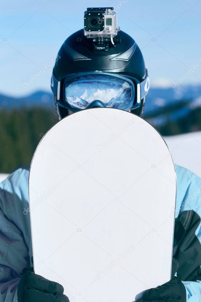 Snowboarder with action camera on a helmet. Close up Portrait of snowboarder in Carpathian Mountains, Bukovel Snowboarder. A mountain range reflected in the ski mask. wearing ski glasses