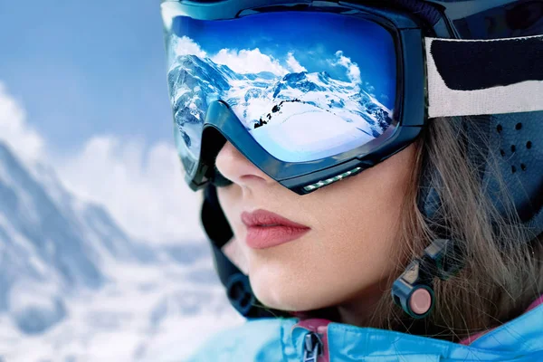 在高山和蓝天的背景下滑雪胜地的年轻妇女的画像 在滑雪面具反射的山范围 — 图库照片