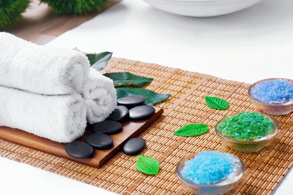 Beautiful spa and wellness setting composition on massage table in relax center on blackboard with copy space.Towel, Salt, Plumeria Flower, Hot stones Bowl for spa therapy.Spa  products