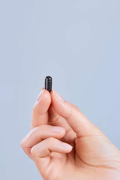 Siyah aktif karbon kapsül gıda zehirlenmesi tedavisi - Image.Vitamins ve Diyet Takviyeler için tutan el.