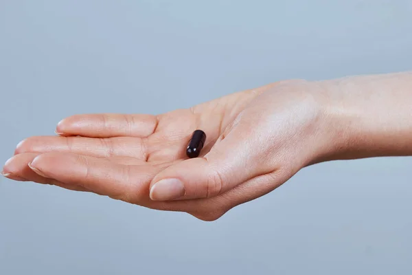 Hand holding black activated carbon capsule  for food poisoning treatment - Image.Vitamins And Dietary Supplements.