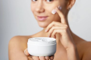 Yaklaşık yüz kremi uygulamak için bir kadının elleri. Moisturizing Lotion.Close-up genç tutan uygulama kızın güzel yüz nemlendirici krem