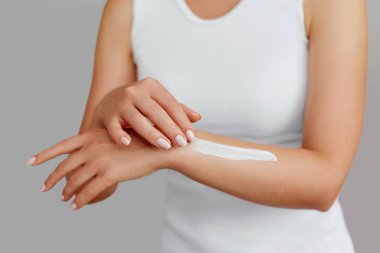 Krem tutarak ve nemlendirici el kremi uygulama kadın el closeup çekim. Güzel eller krema ile. El Cilt Bakımı. Bir kadının vücut losyonu kollarında kullanır. Güzellik ve vücut bakım kavramı 