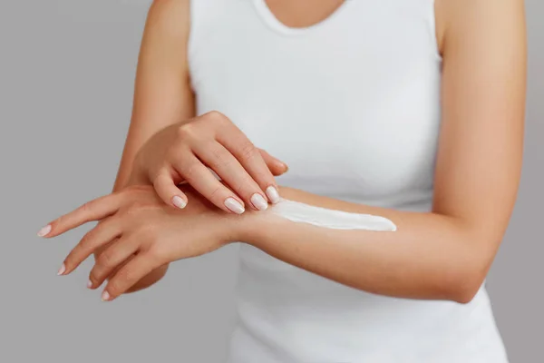 Closeup shot of woman hands holding cream and applying moisturizing hand cream. Beautiful female hands with cream. Hand Skin Care. A woman uses body lotion on your arms. Beauty And Body Care Concept