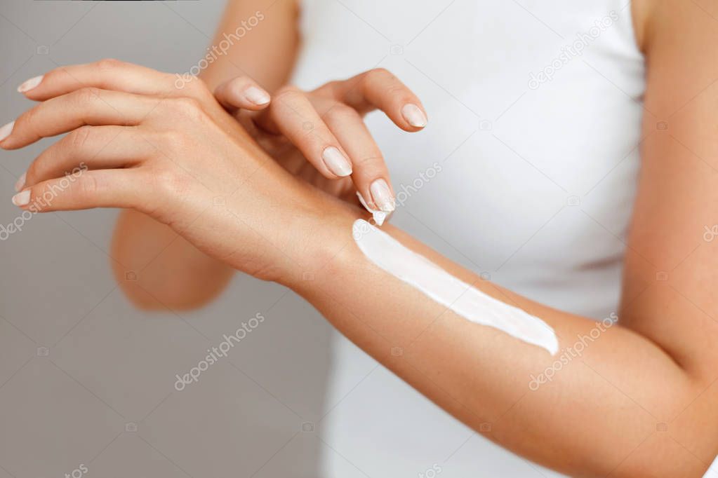 Closeup of female hands applying hand cream.Hand Skin Care.  Women use body lotion on your arms.  Beauty And Body Care Concept
