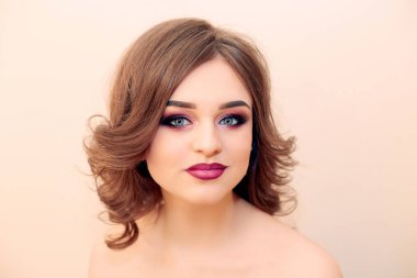 Kıvırcık saçlı, moda lüks makyaj güzel model kız. Güzel genç kadın temiz taze cilt ile kapatın. Cilt bakımı yüz. Kozmetik. Güzellik kadını yüz portre.