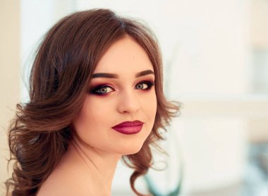 Kıvırcık saçlı, moda lüks makyaj güzel model kız. Güzel genç kadın temiz taze cilt ile kapatın. Cilt bakımı yüz. Kozmetik. Güzellik kadını yüz portre.