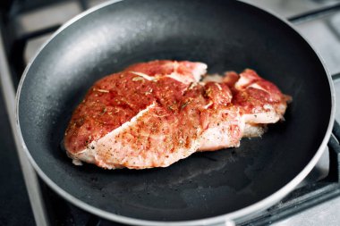 Dökme demir tavada rozbif, et sadece üst tarafı hala kırmızı kızgın yağ için eklendi