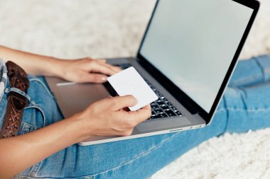 Kredi kartı tutan ve bir dizüstü bilgisayarda web, arama bilgi tarama, evde çalışma alanı olan yere, ödeme, oturma bir dizüstü bilgisayar kullanarak erkek çalışan kadın. Bloglama kavramını. Modern teknolojiler. Üstten Görünüm.