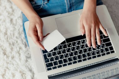 Shoping online, ödeme, kredi kartı tutan ve bir dizüstü bilgisayarda web, arama bilgi tarama, evde çalışma alanı olan yere, oturma bir dizüstü bilgisayar kullanarak erkek çalışan kadın. Bloglama kavramını. Modern teknolojiler. Üstten Görünüm.